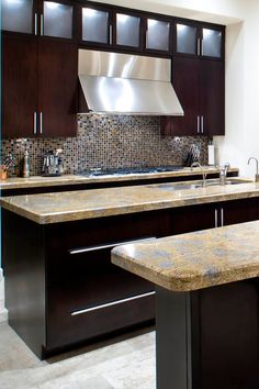 a kitchen with marble counter tops and dark wood cabinets