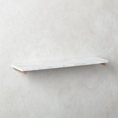 a white marble shelf with gold trim against a wall