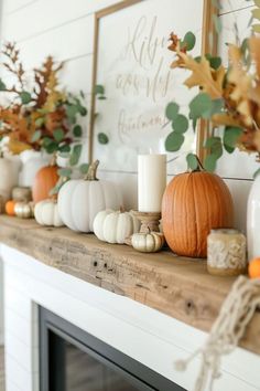 a mantle with candles, pumpkins and greenery on it