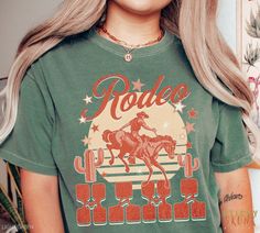 "Be your best Rodeo Queen self in this comfy vintage-inspired Comfort Colors Western tee. For that country cowgirl or rodeo mom in your life, this makes a great gift as well! 🦨 --- ABOUT THIS ITEM --- ✦ Comfort Colors Garment-Dyed Unisex Crewneck T-shirt ✦ 100% Ringspun Cotton ✦ DTG-printed so no cracking or peeling ✦ Water-based ink, safe for children and pets ✦ Colors of design and shirt may vary depending on monitor/screen settings 🦨 --- SIZING --- ✦ Please consult the size charts before pu Retro Screen Print Tops For Rodeo, Retro Letter Print Tops For Rodeo, Vintage Letter Print Tops For Rodeo, Retro Graphic Print Tops For Rodeo, Vintage Relaxed Fit Tops For Rodeo, Vintage Crew Neck Top For Rodeo, Western Prints, Cowgirl Gifts, Western Tee