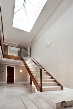 a staircase leading up to a skylight in a modern home with white walls and flooring