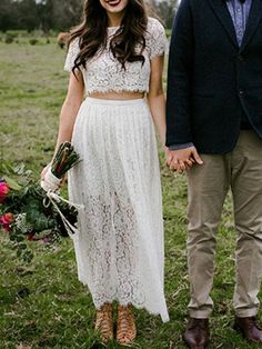 a man and woman standing next to each other on a lush green field holding hands