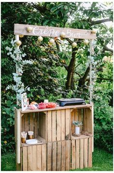 an outdoor bar is set up in the grass with fruit and vegetables on it's stand