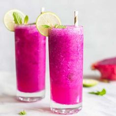 two glasses filled with purple liquid and lime slices