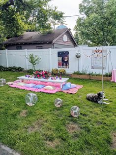 a dog laying on the grass in front of a table with bubble balls around it