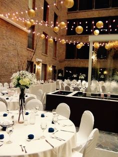 tables and chairs are set up for a formal function in an indoor setting with lights strung from the ceiling