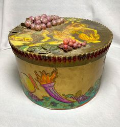 an ornately decorated metal box with flowers on it's lid, sitting on a white surface