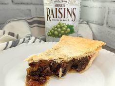 a piece of pie sitting on top of a white plate next to a bottle of raisins