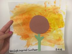 a child's hand holding up a piece of paper that has been made to look like a flower