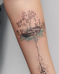 a woman's arm with a tree and boat tattoo on it