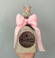 a person holding up a bottle with a pink bow on it's head and the words donjullo 70 written on it