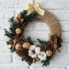 a wreath with pine cones, cotton balls and cinnamons hanging on a brick wall