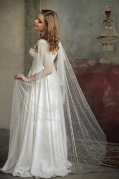 a woman in a white wedding dress with a long veil on her head and shoulders