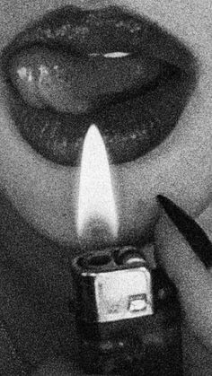 a black and white photo of a person holding a cell phone with a lit candle in front of them