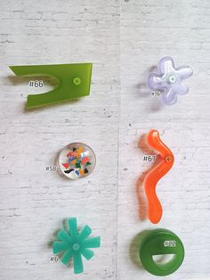 four different colored plastic objects on a white brick wall with numbers and symbols attached to them