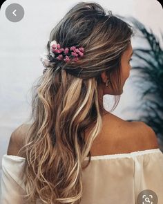 a woman with long hair and pink flowers in her hair is looking off to the side