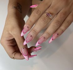 a woman's hands with pink and white nail designs on their nails, holding a diamond ring