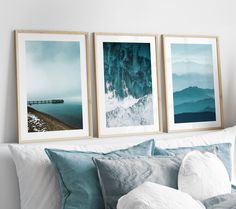 three framed pictures hang on the wall above a bed with blue pillows and white sheets