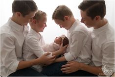 a group of young men holding a baby in their lap while sitting next to each other