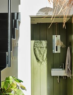 a bathroom with green walls and white sink next to a plant in a pot on the floor