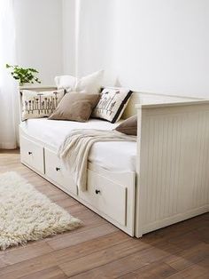 a white day bed sitting on top of a hard wood floor next to a window