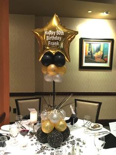 the table is set with black and gold balloons