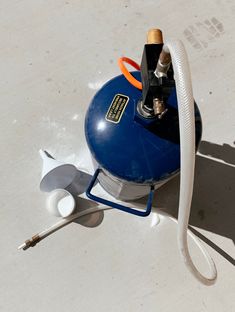 a blue propaner sitting on top of a white floor next to a hose