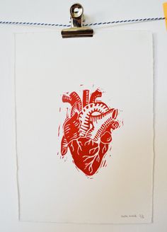 a red and white drawing of a human heart hanging on a wall with blue string