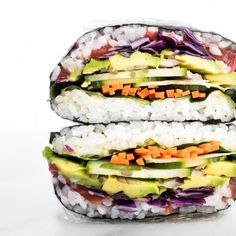 two sushi rolls stacked on top of each other with vegetables and avocado