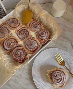 there is a box of cinnamon rolls with icing on the table next to it