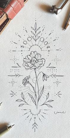 a drawing of flowers on paper with some pens and pencils next to the ink