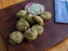 a wooden cutting board topped with cookies next to a bowl of dip