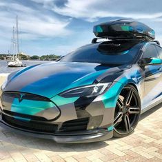 a blue and silver car parked next to the ocean