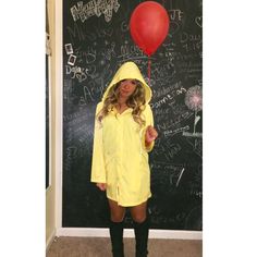 a woman in a yellow raincoat holding a red balloon