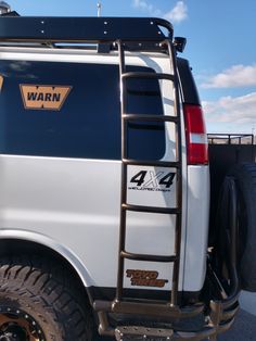 the back end of a white truck with a ladder on it's flatbed