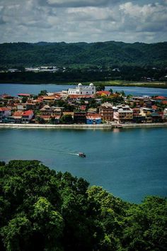 an aerial view of a small town on the water's edge with trees and mountains in the background