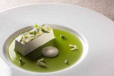 a white plate topped with green liquid and food