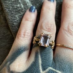 a woman's hand with two rings and an emerald colored stone on the ring