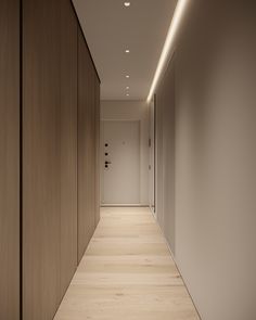 an empty hallway with wood paneling and lighting on either side of the room is lit by recessed lights