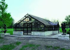 a glass house in the middle of a park with statues and sculptures on it's sides