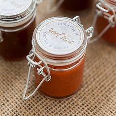 small jars filled with jam sitting on top of a burlied tablecloth covered surface