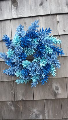 a blue wreath hanging on the side of a wooden wall next to a building with gray shingles