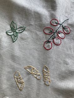 three embroidered objects are sitting on top of a piece of cloth, with the word love spelled out in small letters