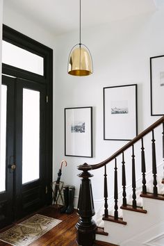 an entryway with pictures on the wall and stairs leading to another room that has been decorated in black and white