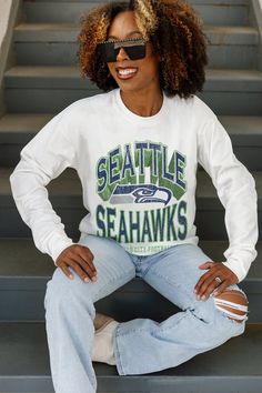 a woman sitting on some steps with her hands on her hips and wearing sunglasses that read seattle seahawks