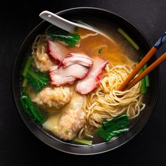 a bowl filled with meat and noodles next to chopsticks