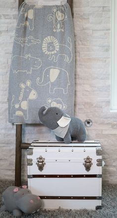 an elephant stuffed animal sitting on top of a trunk in front of a towel rack