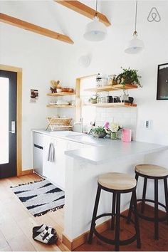 a kitchen with two stools next to a counter top and shelves on the wall