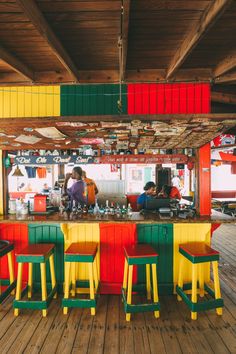 brightly colored tables and stools are lined up on the wooden floor in an outdoor restaurant