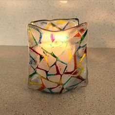 a glass candle holder sitting on top of a counter next to a white wall and floor